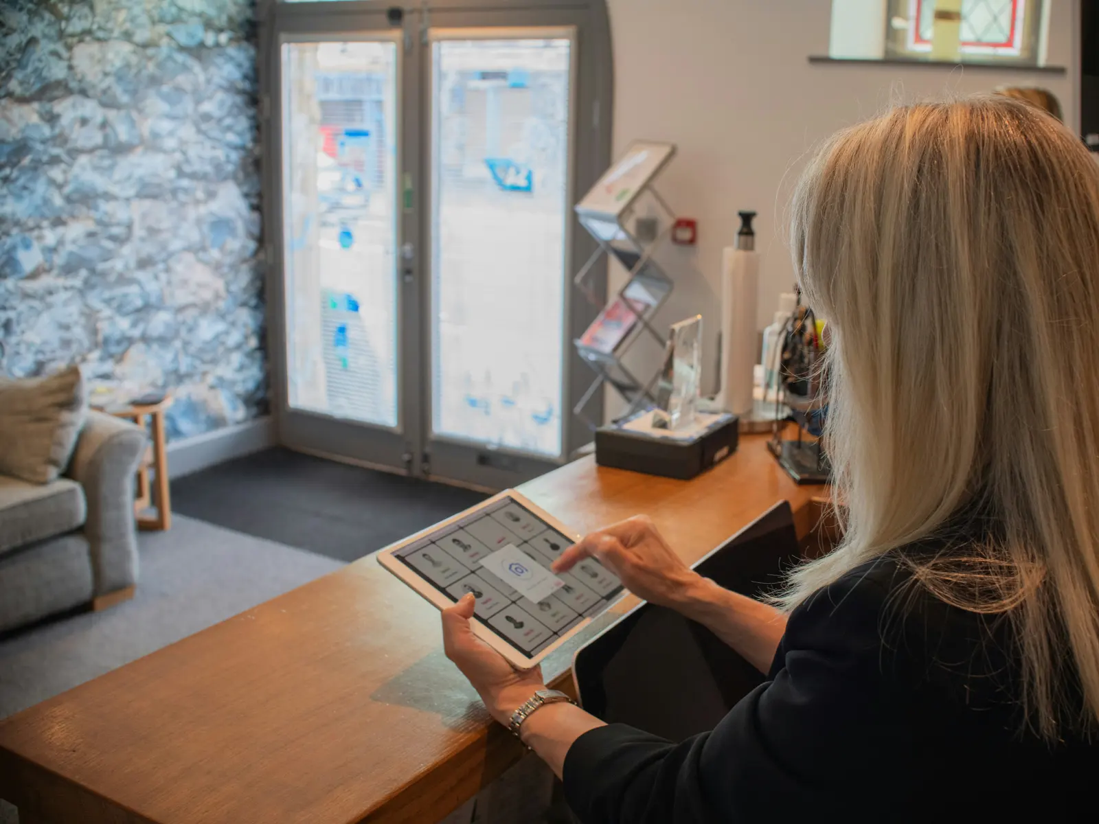 A receptionist uses a tablet at the front desk of a wellness practice