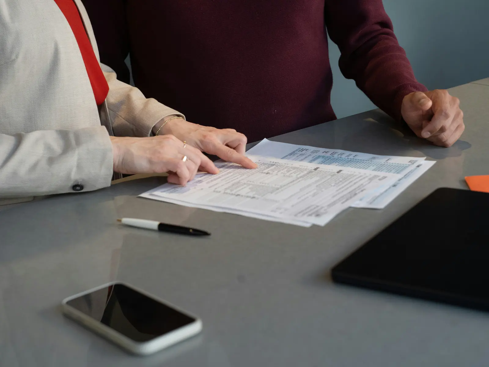 Two people review printed forms together across a table